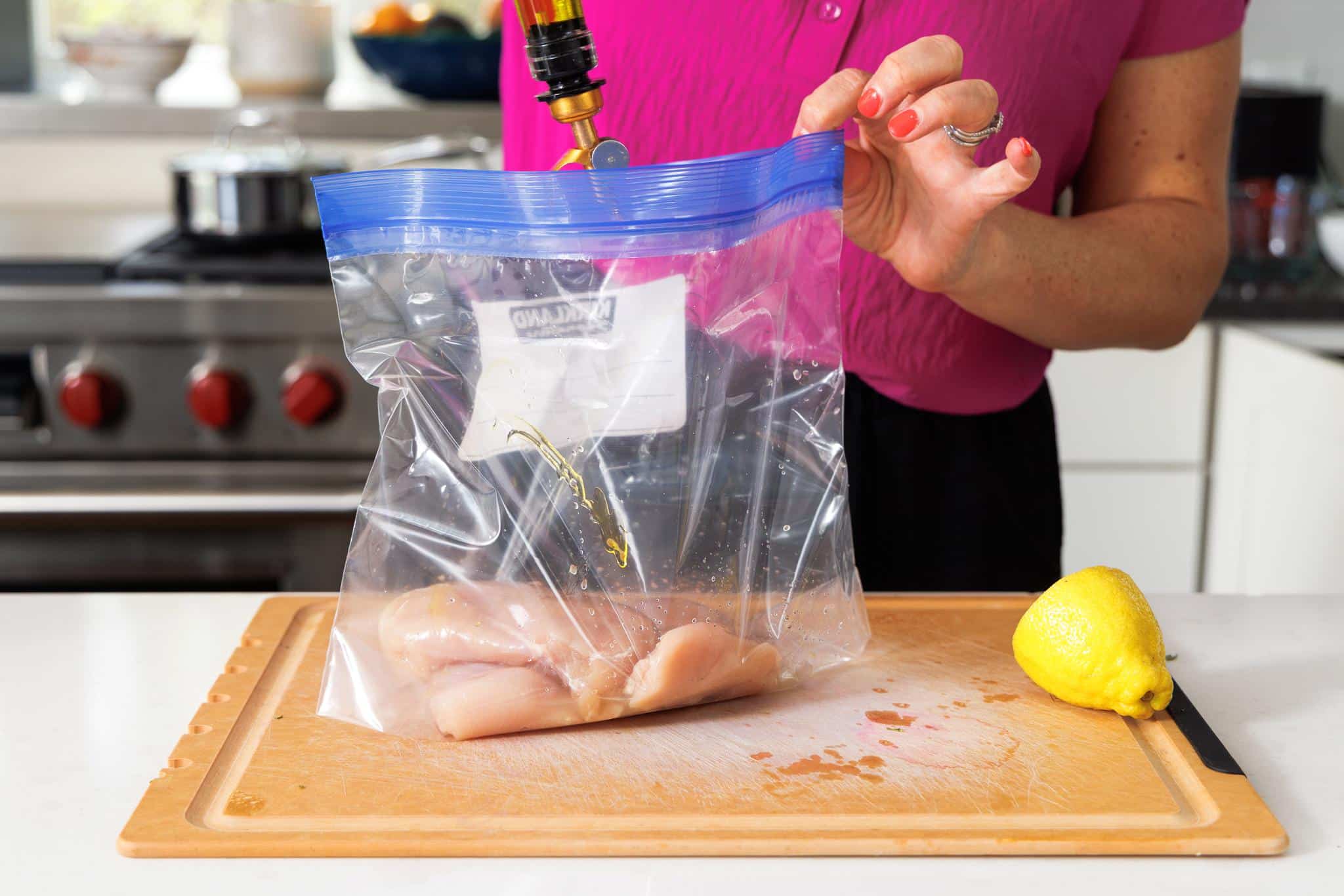 Adding olive oil to bag with chicken breast.