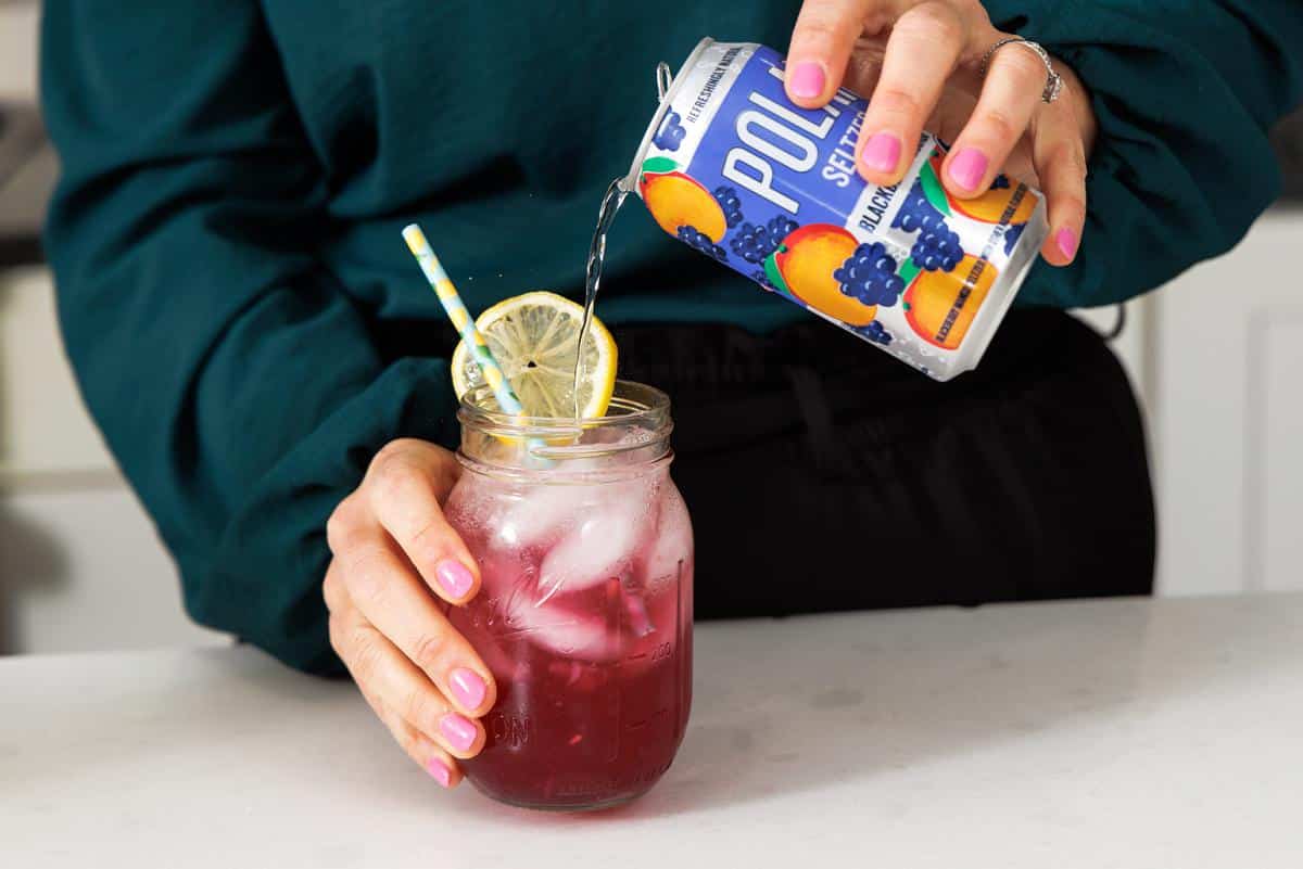 Pouring seltzer water into cocktail.