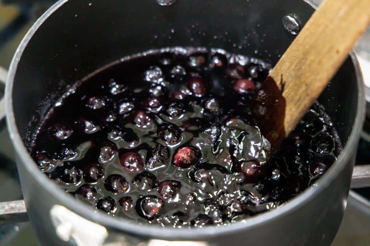 Stirring blueberries in a pot on the stove.