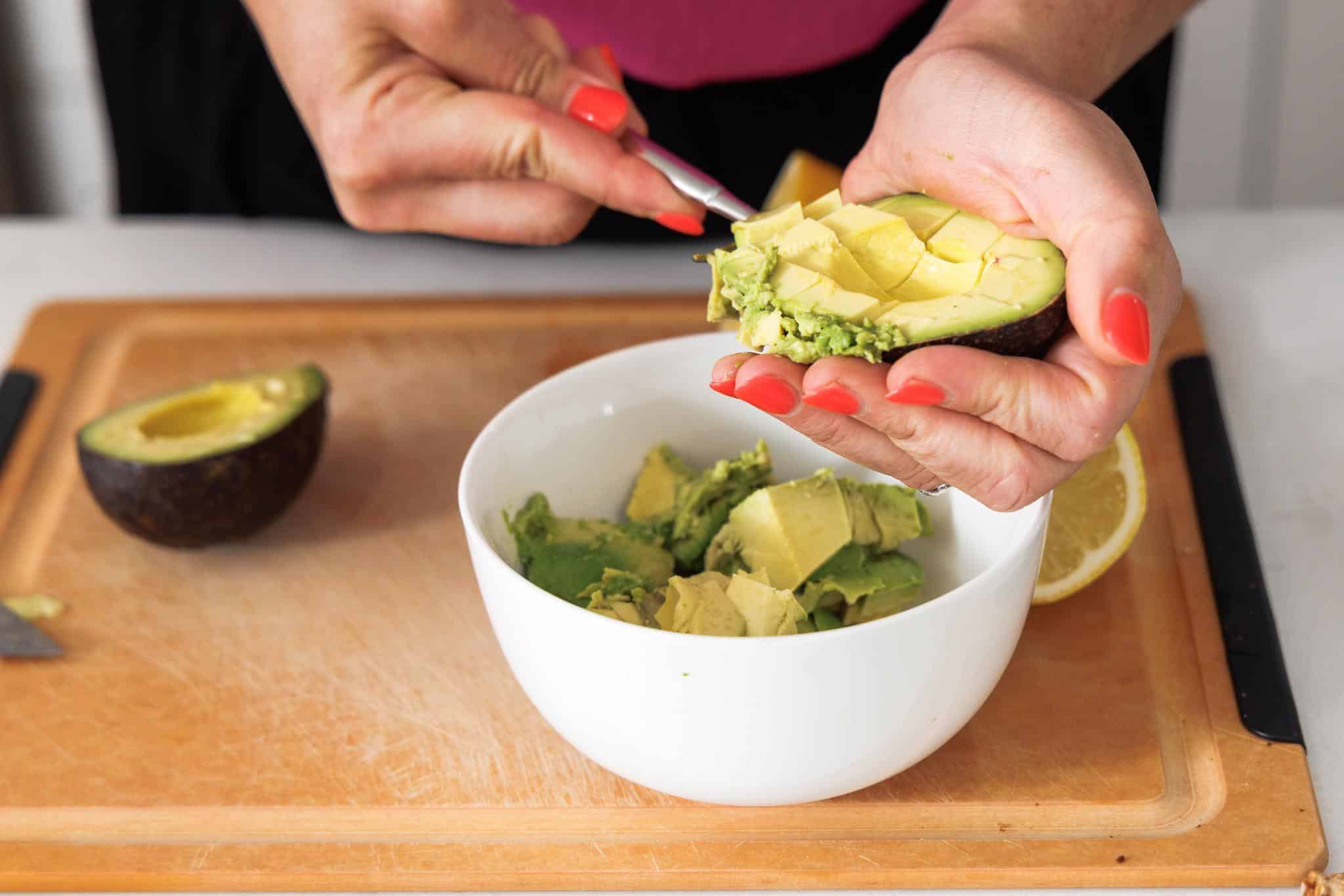 Cleaning out avocado into a small bowl.