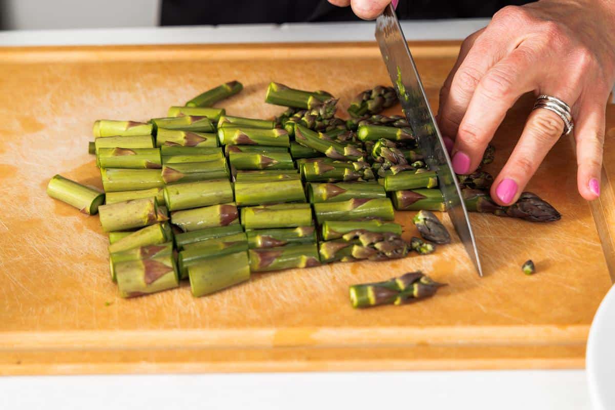 Chopping asparagus spears into smaller pieces.