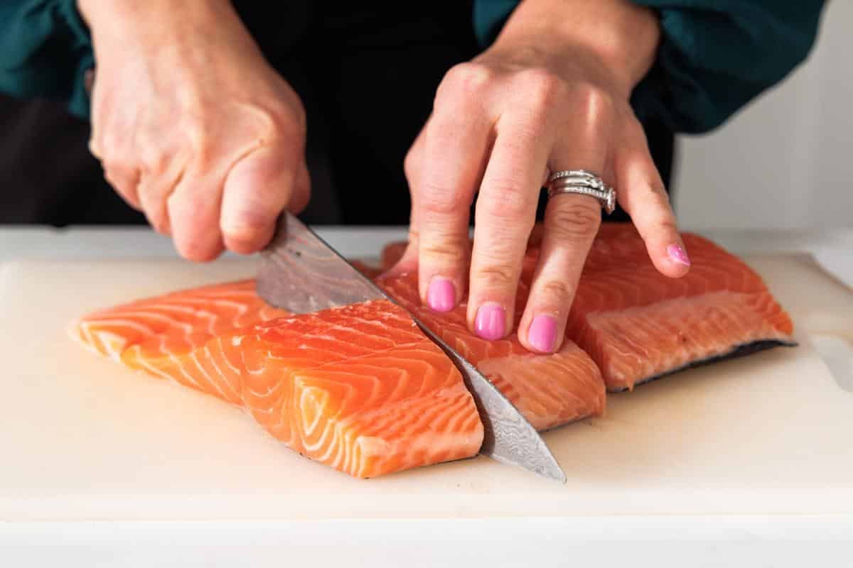 Cutting large salmon fillet into smaller fillets.
