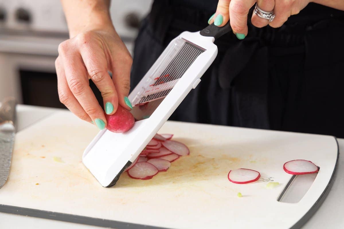 Using a madoline to slice radishes.