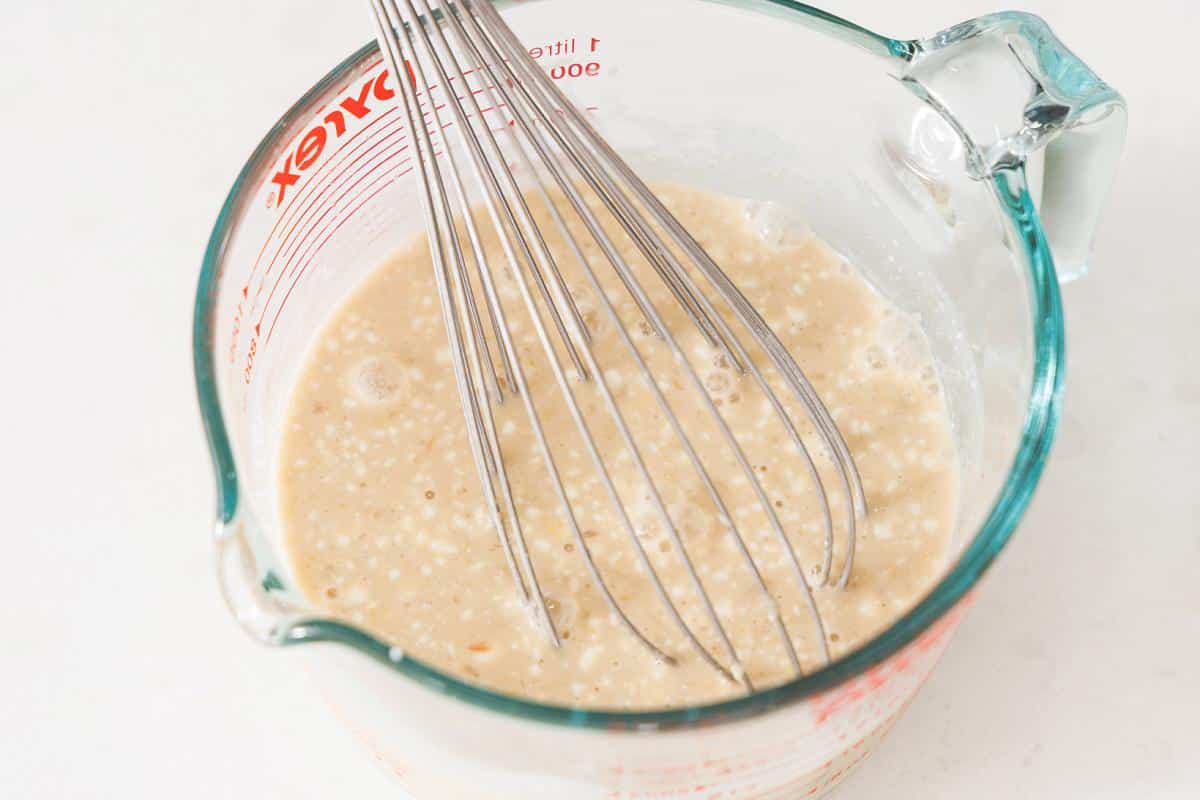 Whisking together Thai green curry sauce in a large measuring cup.