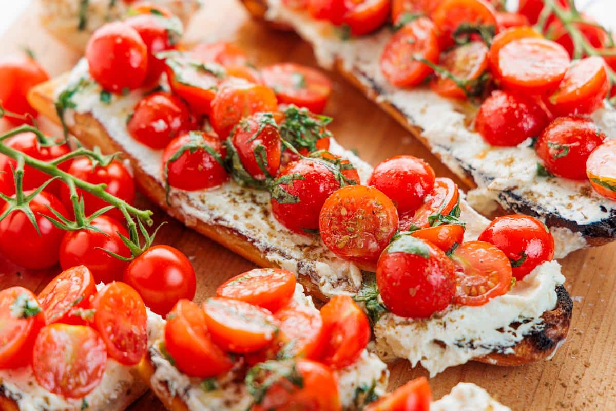 Cherry tomato bruschetta with whipped feta on Italian bread loaves.