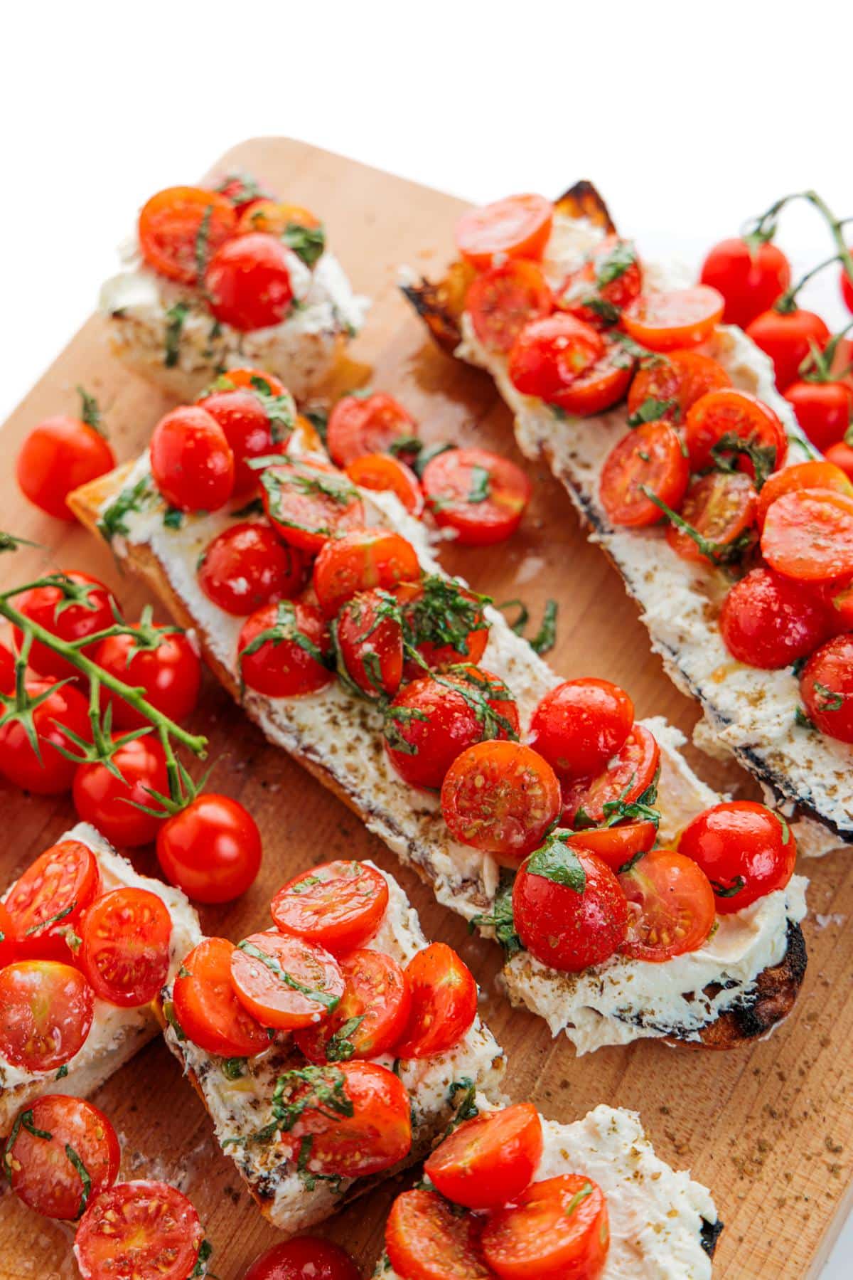 Cherry tomato bruschetta with whipped feta on Italian bread loaves garnished with sea salt.