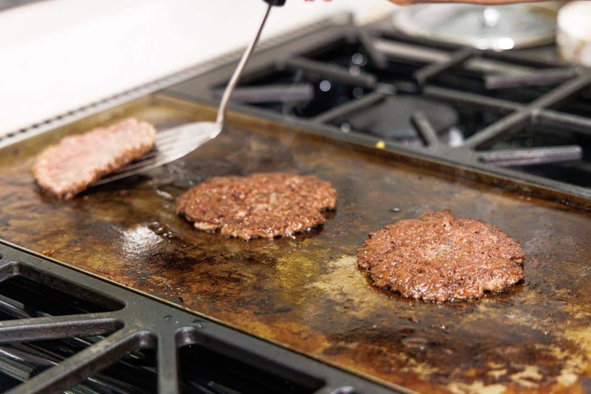 Flipping Greek smash burgers on griddle.