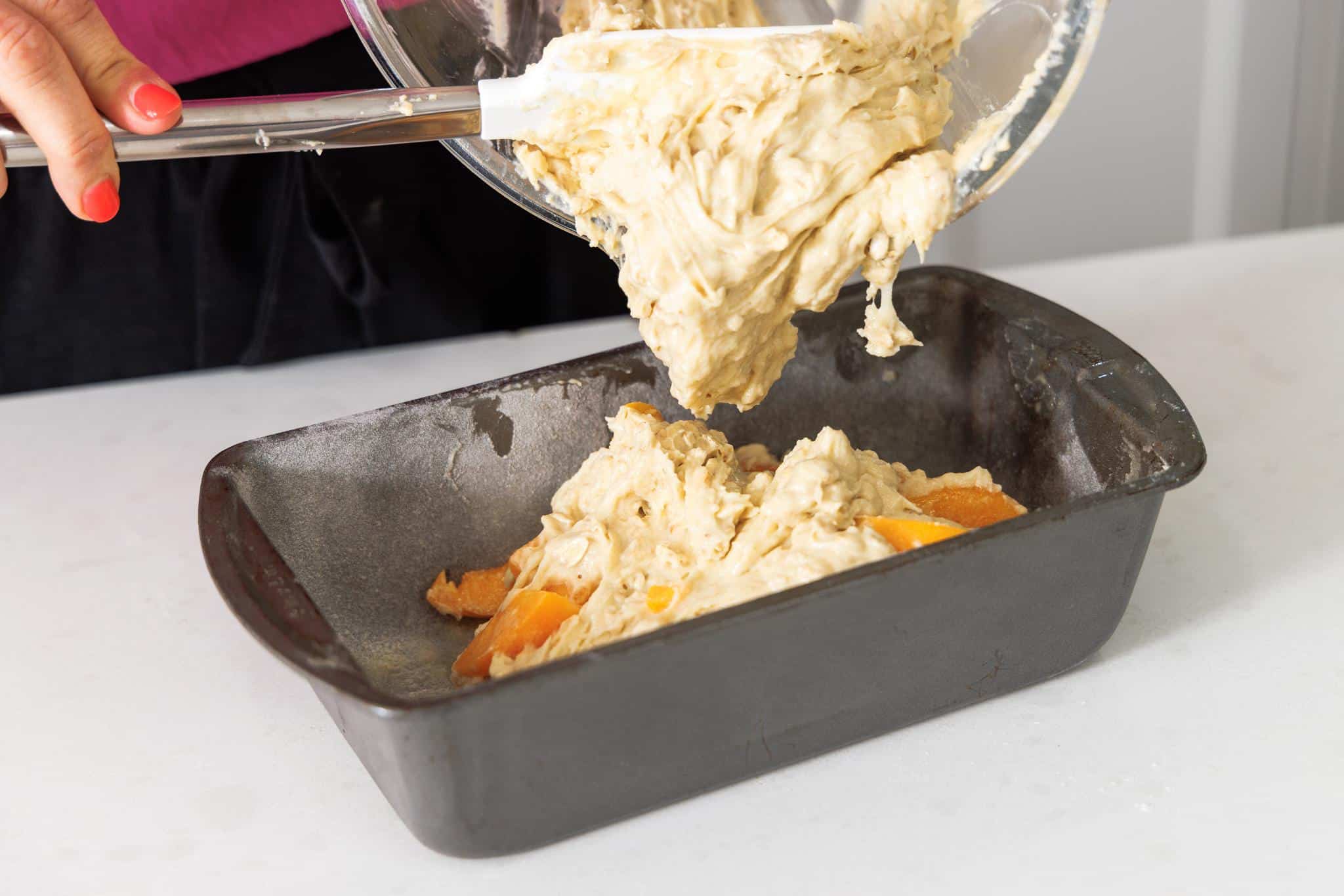 Adding batter for bread to a metal bread tin.