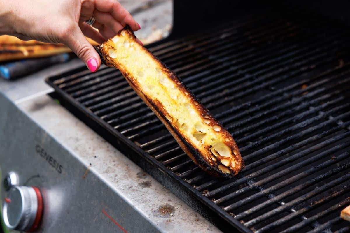 Putting Italian bread half on the grill.