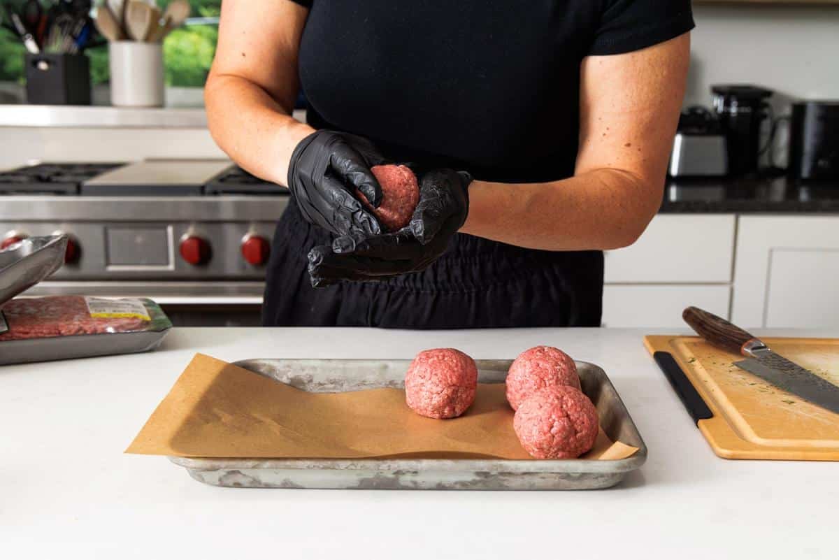 Rolling up balls of ground beef.