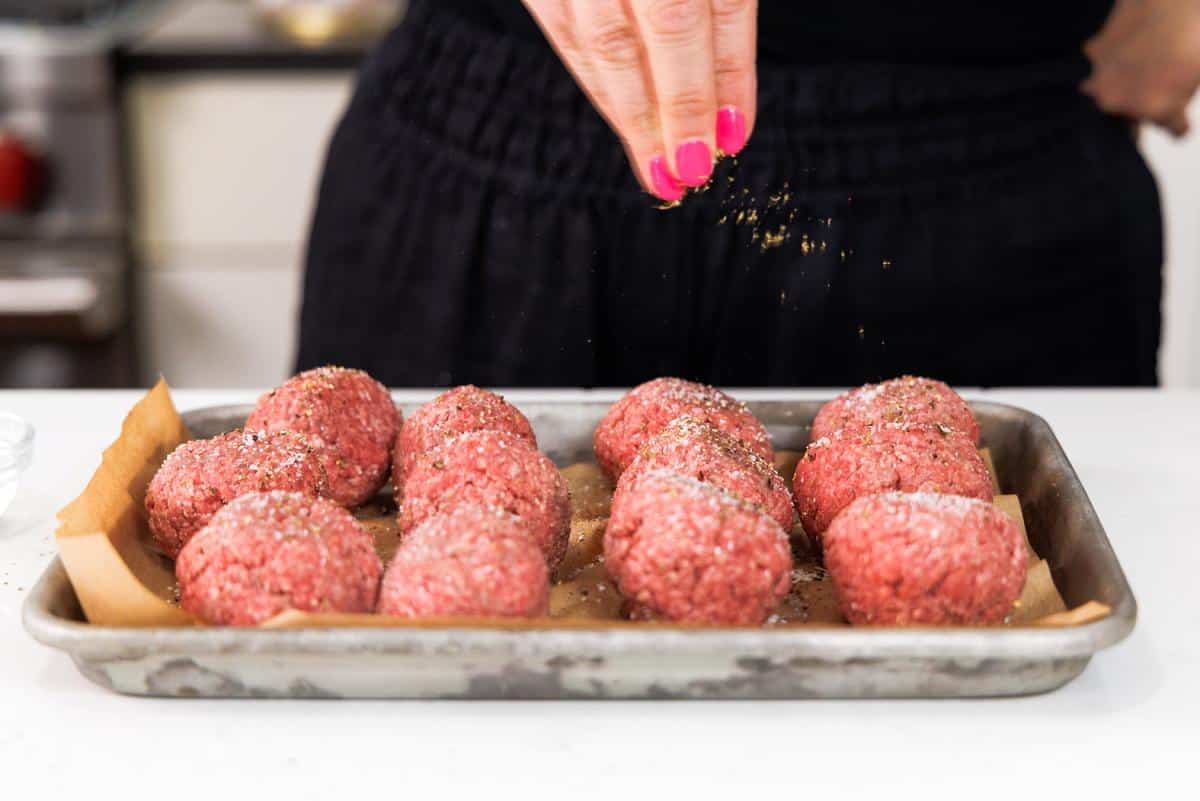 Seasoning ground beef with Greek seasoning.