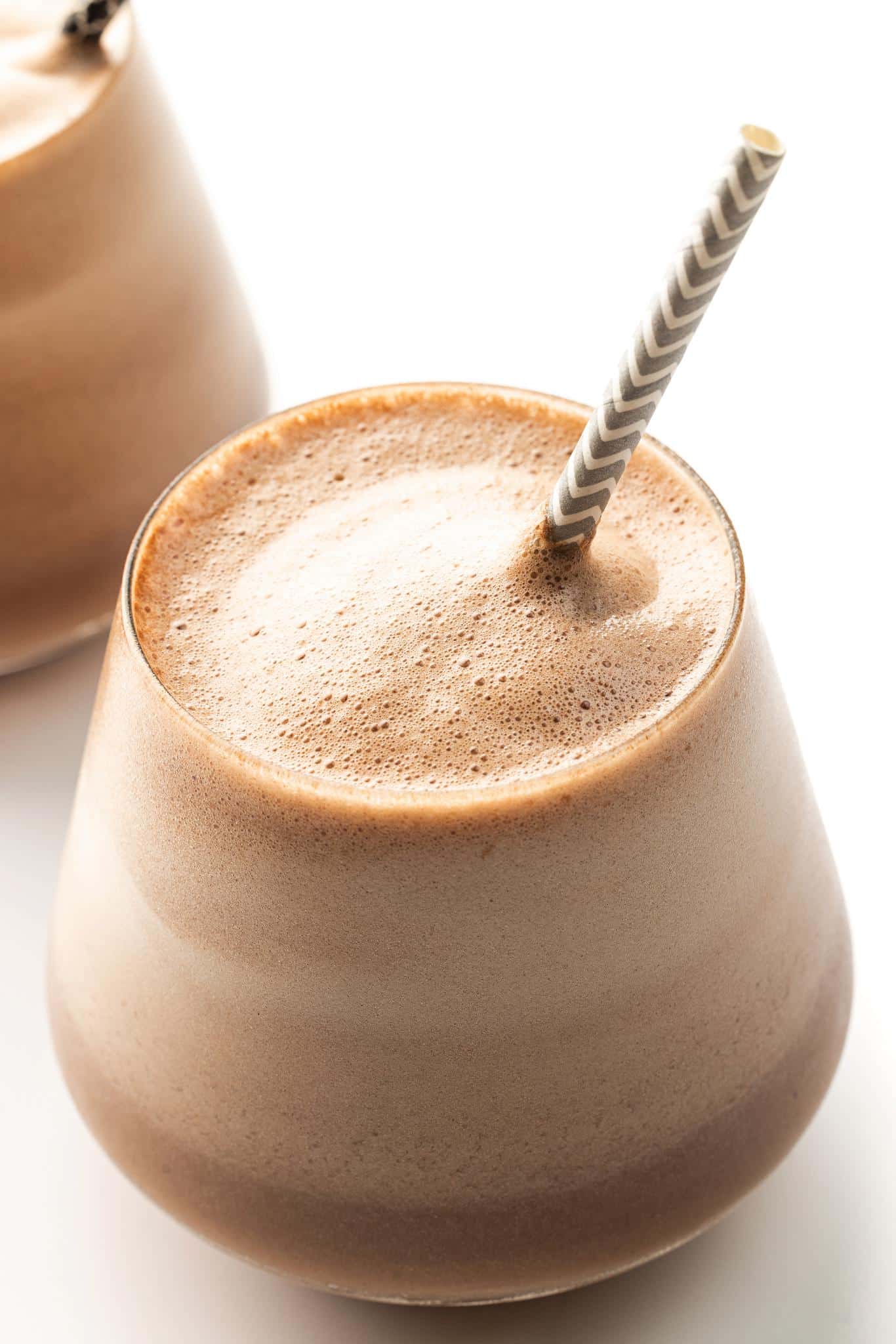 Chocolate espresso protein smoothie in a glass with a straw.
