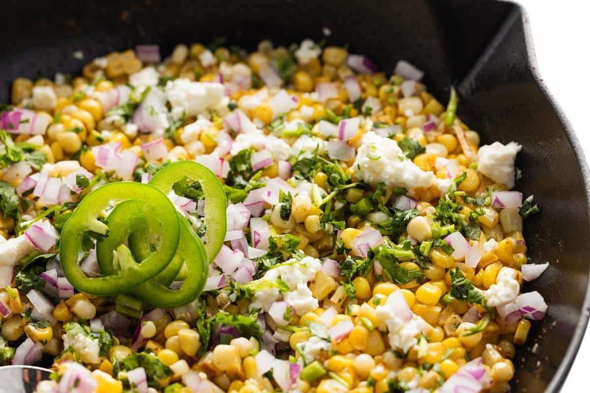 Skillet Mexican street corn in a cast iron with cotija cheese and fresh cilantro.