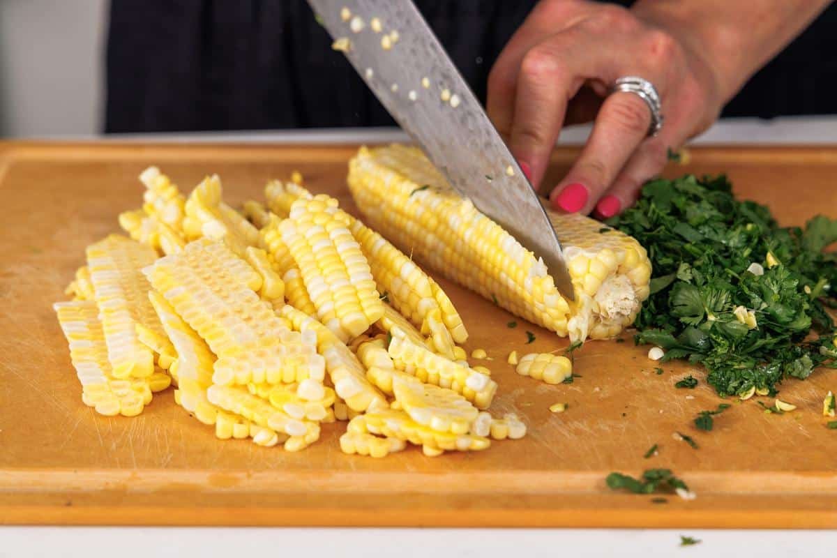Cutting the corn off of a corn cob.